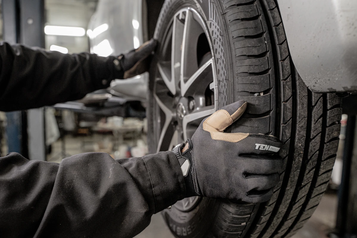 A mechanic working at the wheel of a car raised on a lift in the garage