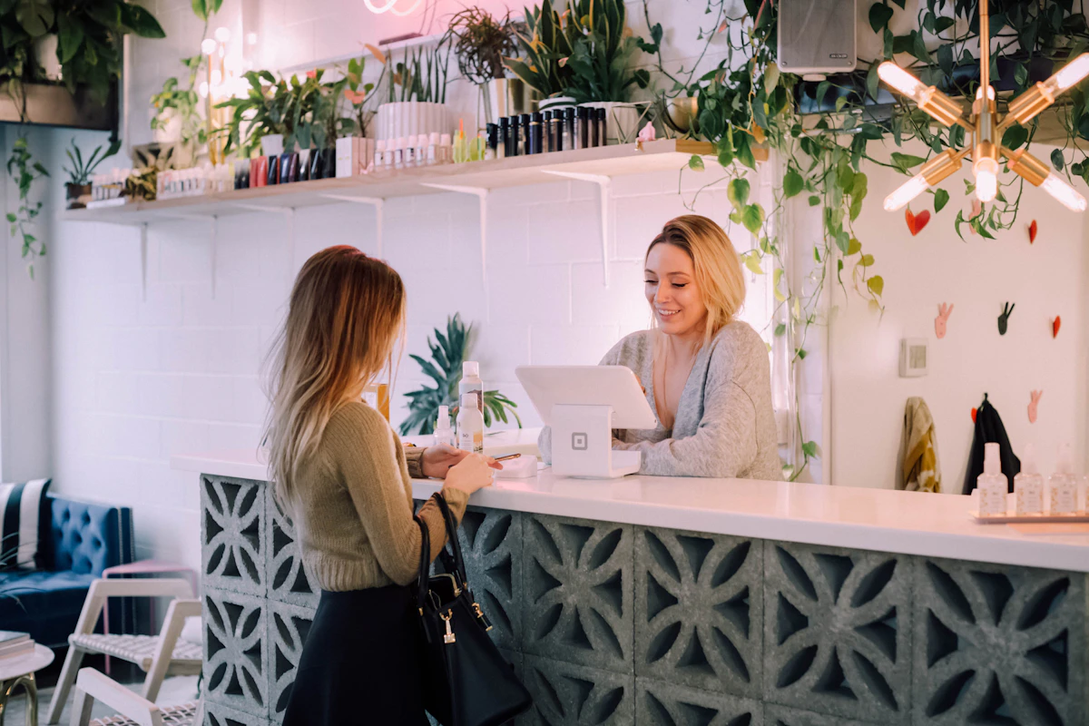 A patient checking in with a smiling receptionist at a bright, plant-lined front desk