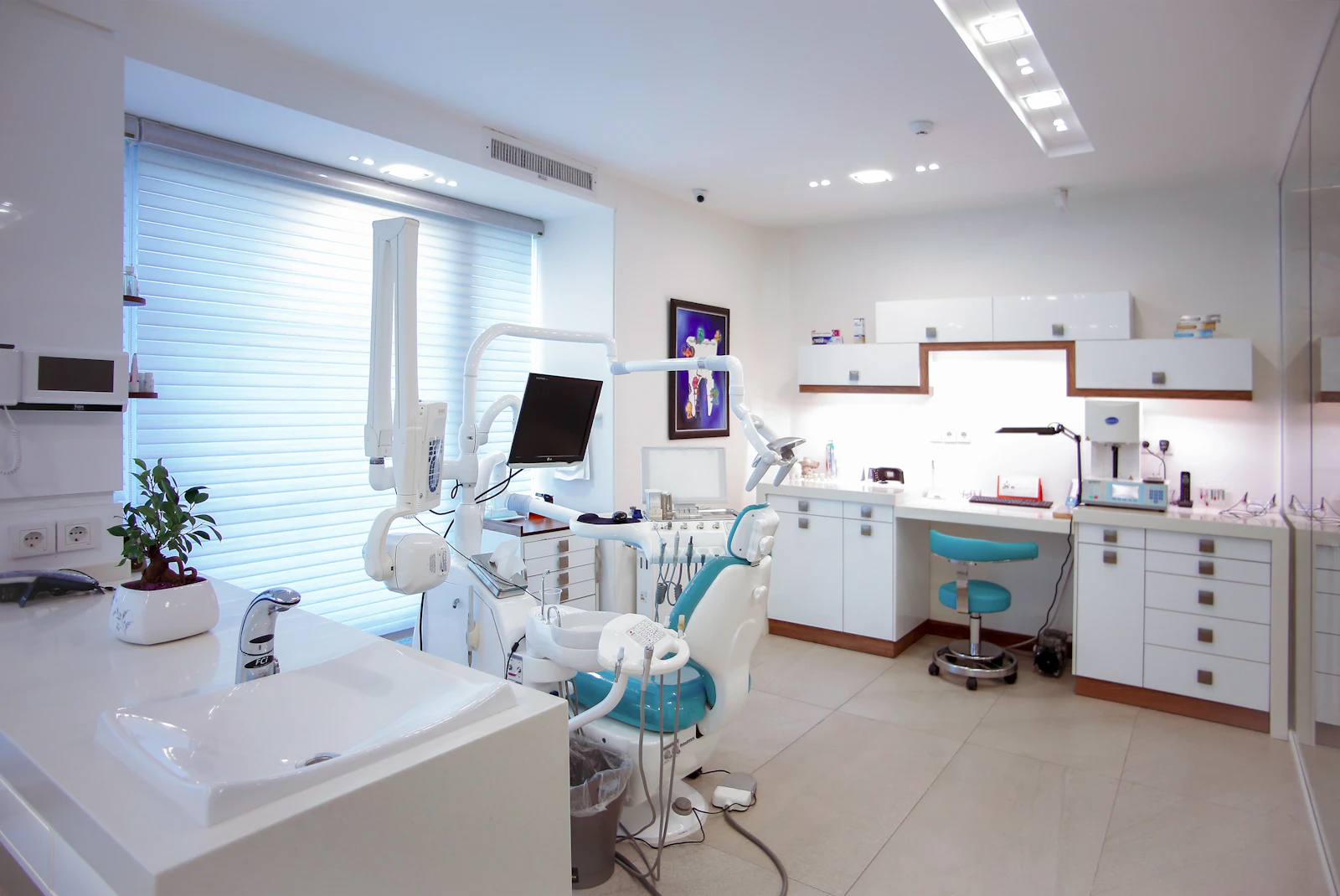 Bright modern dental office with a treatment chair, overhead light and clean white equipment