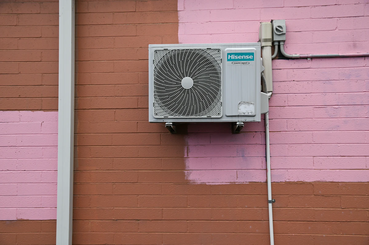 A newly mounted mini-split condenser unit on an exterior brick wall