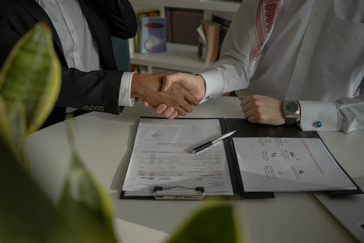 A lawyer and client shaking hands over signed paperwork at a conference table