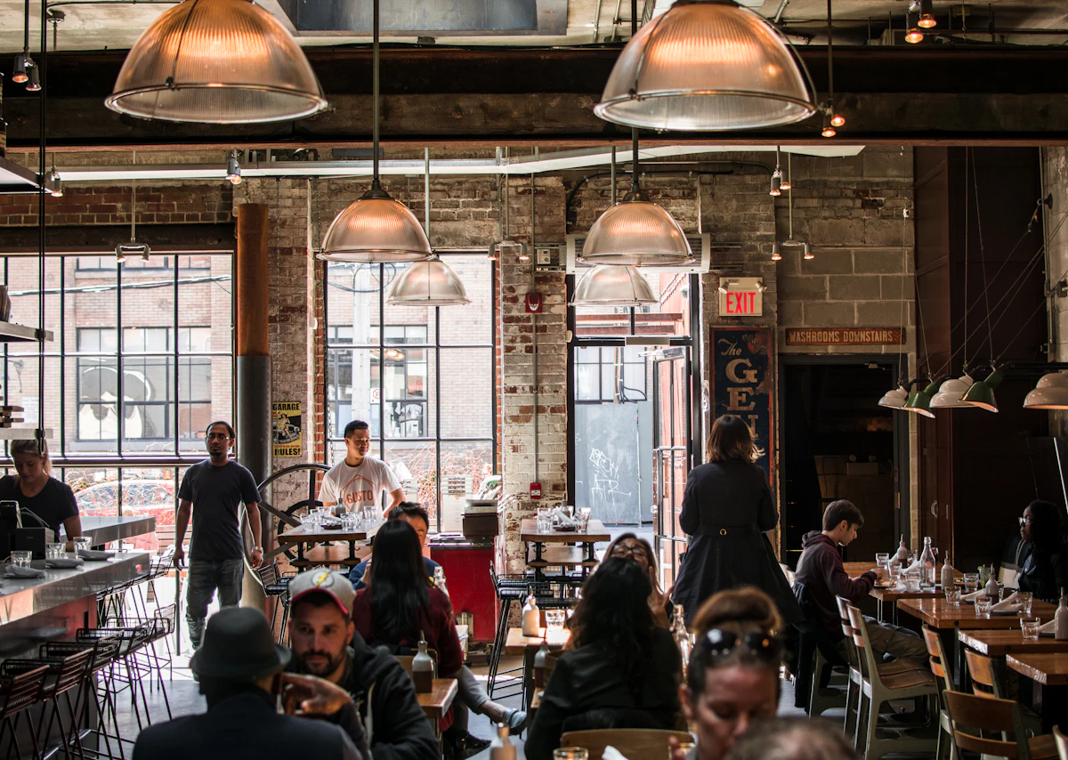 A packed dining room mid-service under warm pendant lights